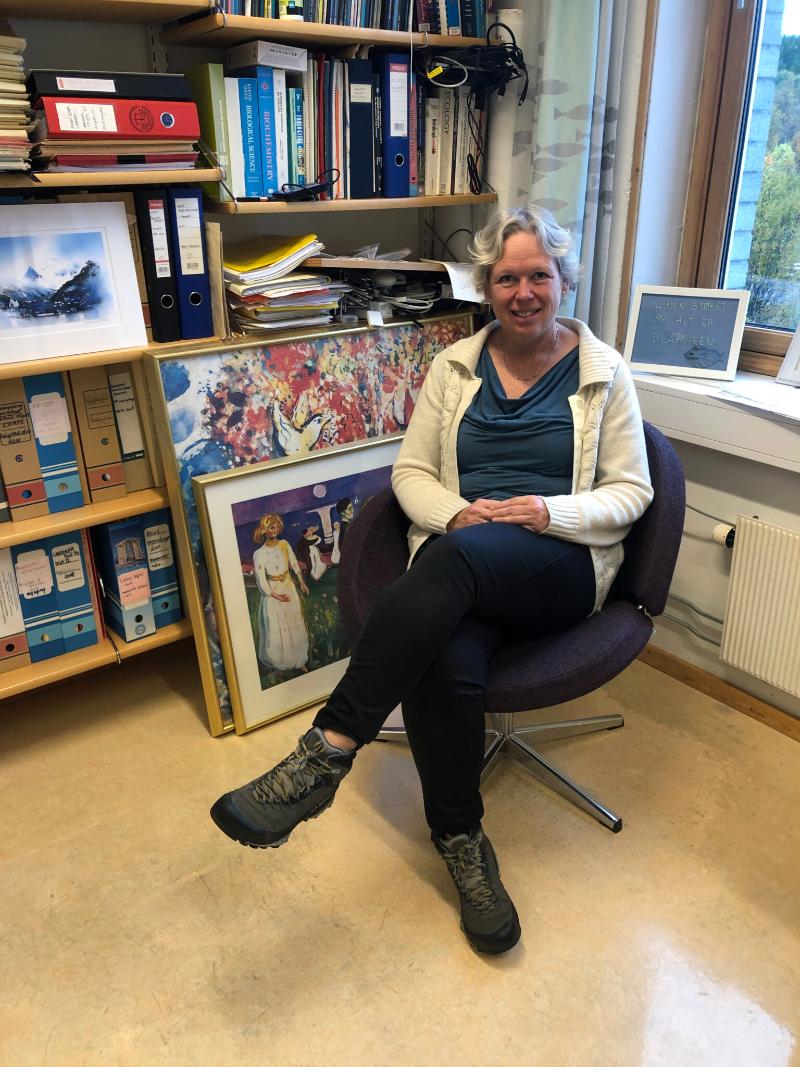 På kontoret.jpeg Marit Reigstad på kontoret omgitt av bilder.